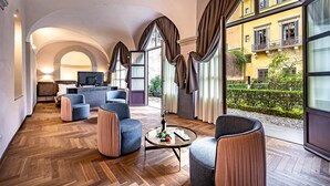 A spacious living room with a herringbone wood floor, modern furniture, and large windows offering a view of a yellow building and greenery. - Hotel La Scaletta Al Ponte Vecchio (Florence)