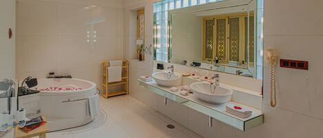 A modern bathroom with a bathtub, two sinks, a vanity, and a large mirror.