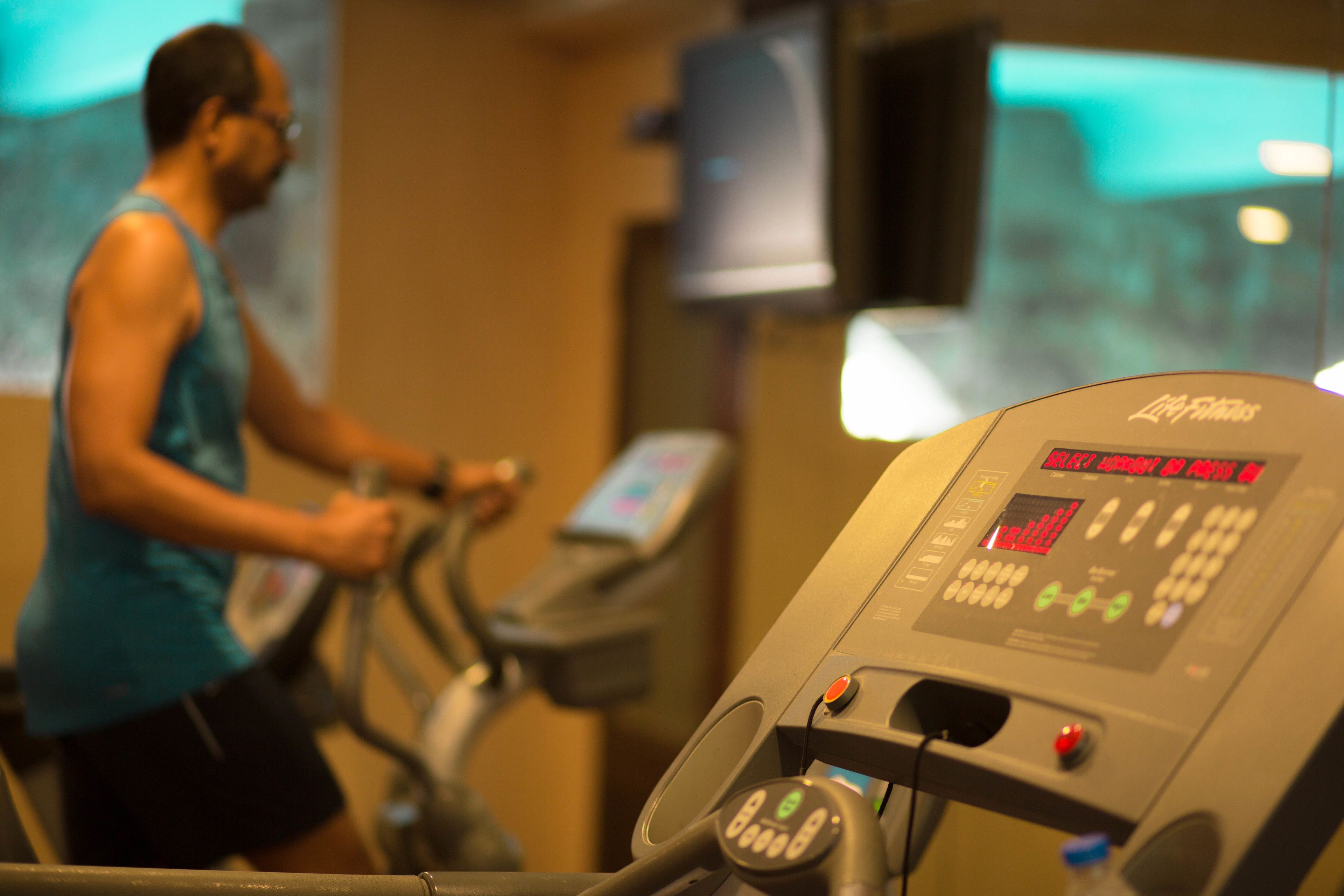 A gym with exercise equipment and a person using a treadmill.