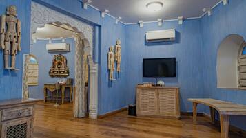 Una habitación con paredes azules, muebles de madera, un televisor y esculturas decorativas.