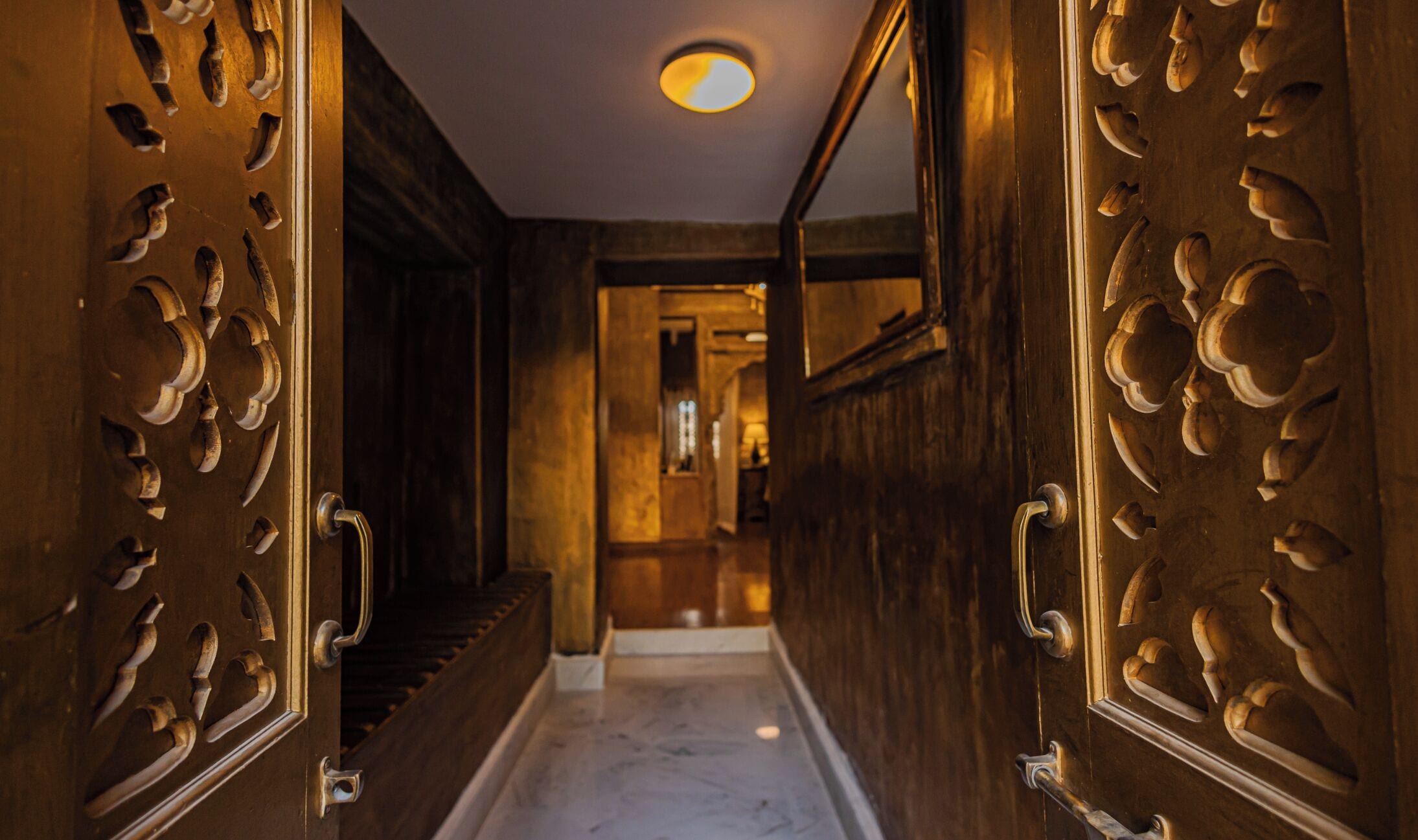 Un couloir doté de portes richement décorées et d’un sol en marbre.