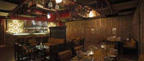 A dimly lit restaurant with wooden furniture, a bar area, and traditional decor.
