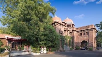 A historic building with domed architecture, a paved entrance, and a tree-lined driveway.