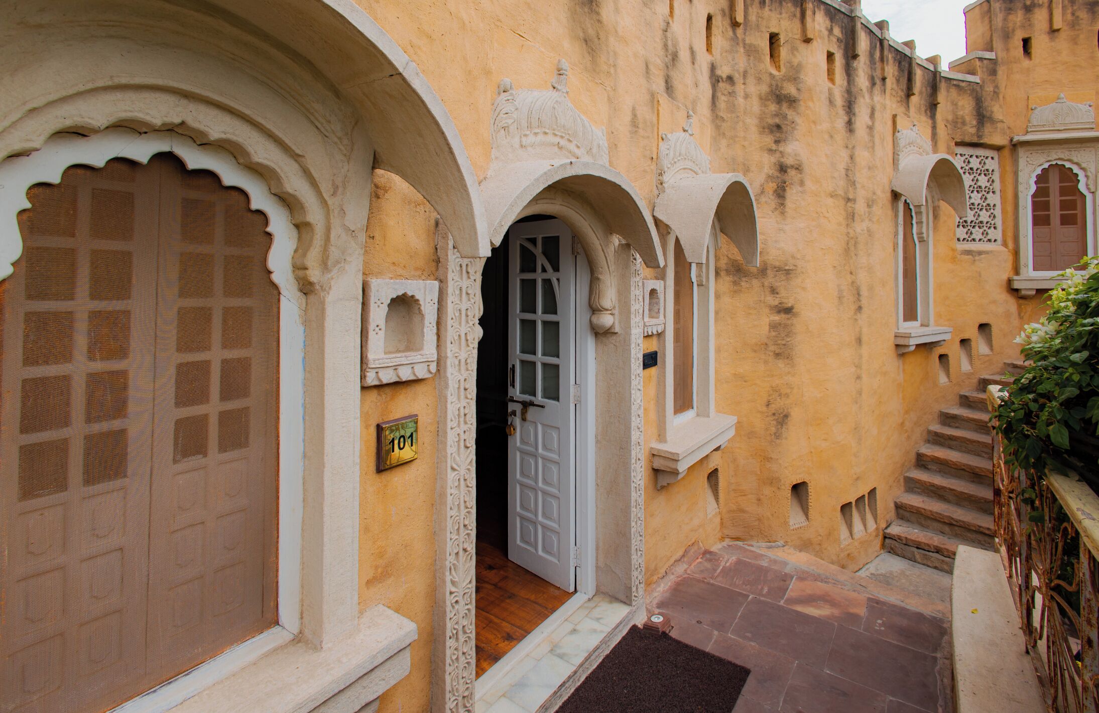 A traditional building with arched doorways and a staircase leading to an upper level.