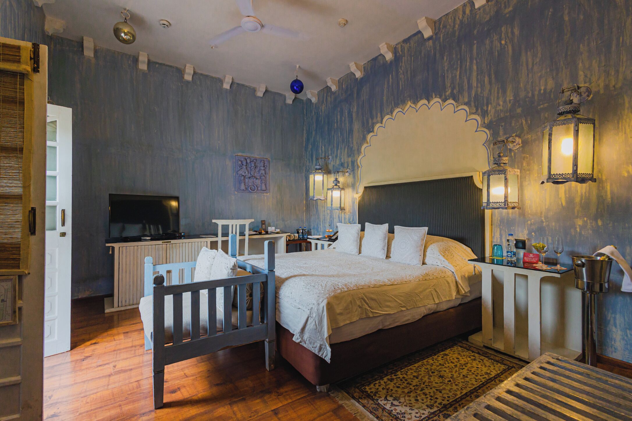 Une chambre à coucher comprenant un lit, des tables de chevet, un téléviseur et des appliques murales décoratives.