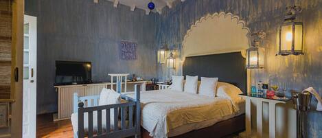 A bedroom with a bed, bedside tables, a television, and decorative wall sconces.