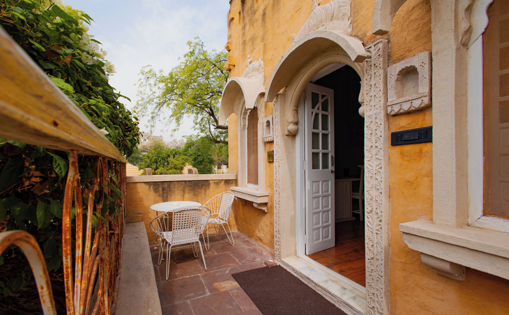 A courtyard with a white door, a small table, and two white chairs.