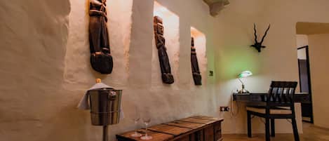 A room with a wooden cabinet, a table, chairs, and wall-mounted sculptures.
