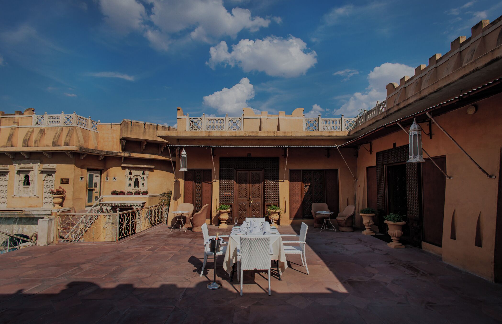 Un patio al aire libre con una mesa dispuesta para comer, rodeado de arquitectura tradicional.