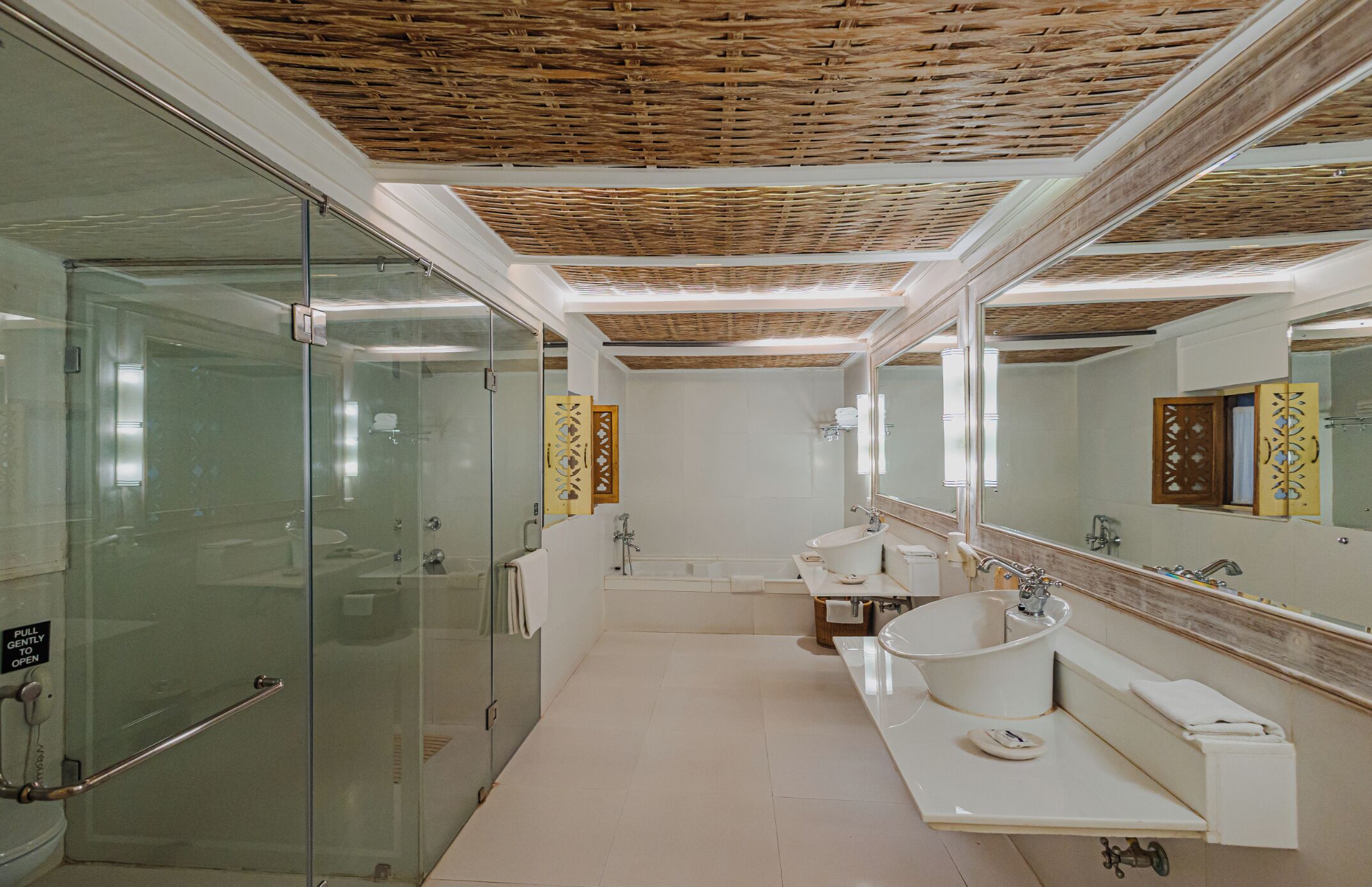 Une salle de bain moderne avec une douche à l’italienne en verre, une grande baignoire et un meuble-lavabo avec un évier et un miroir.