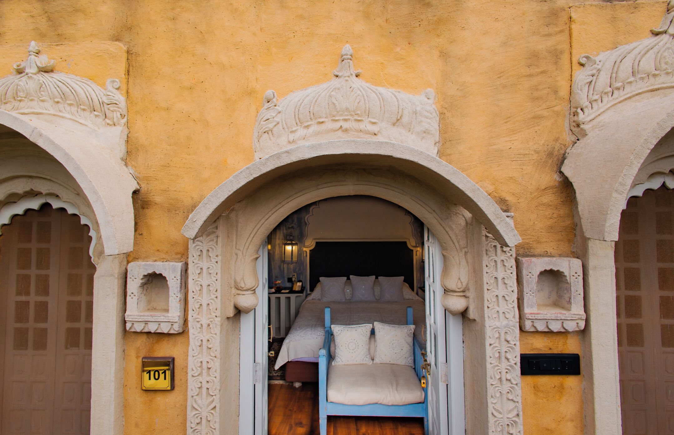 Ein traditionelles Gebäude mit einer verzierten Fassade, ein Bett mit Kissen und einem Hinweisschild.