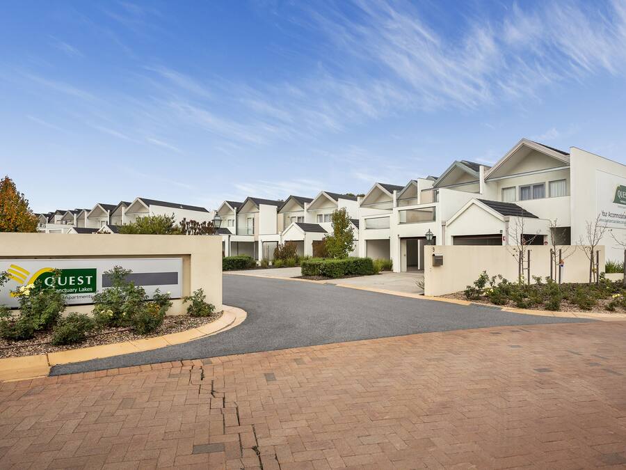 Un complesso residenziale moderno con un cartello che indica 'Quest Sanctuary Lakes Apartments'.