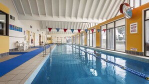 Una piscina con marcas divisorias claras, un cartel de seguridad que indica una profundidad de agua de 1.2 metros y un reloj en la pared.