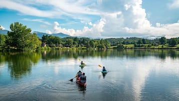 A calm lake with kayaks and a person paddling.