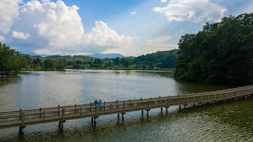 Un puente de madera sobre un lago tranquilo con una ladera boscosa al fondo.