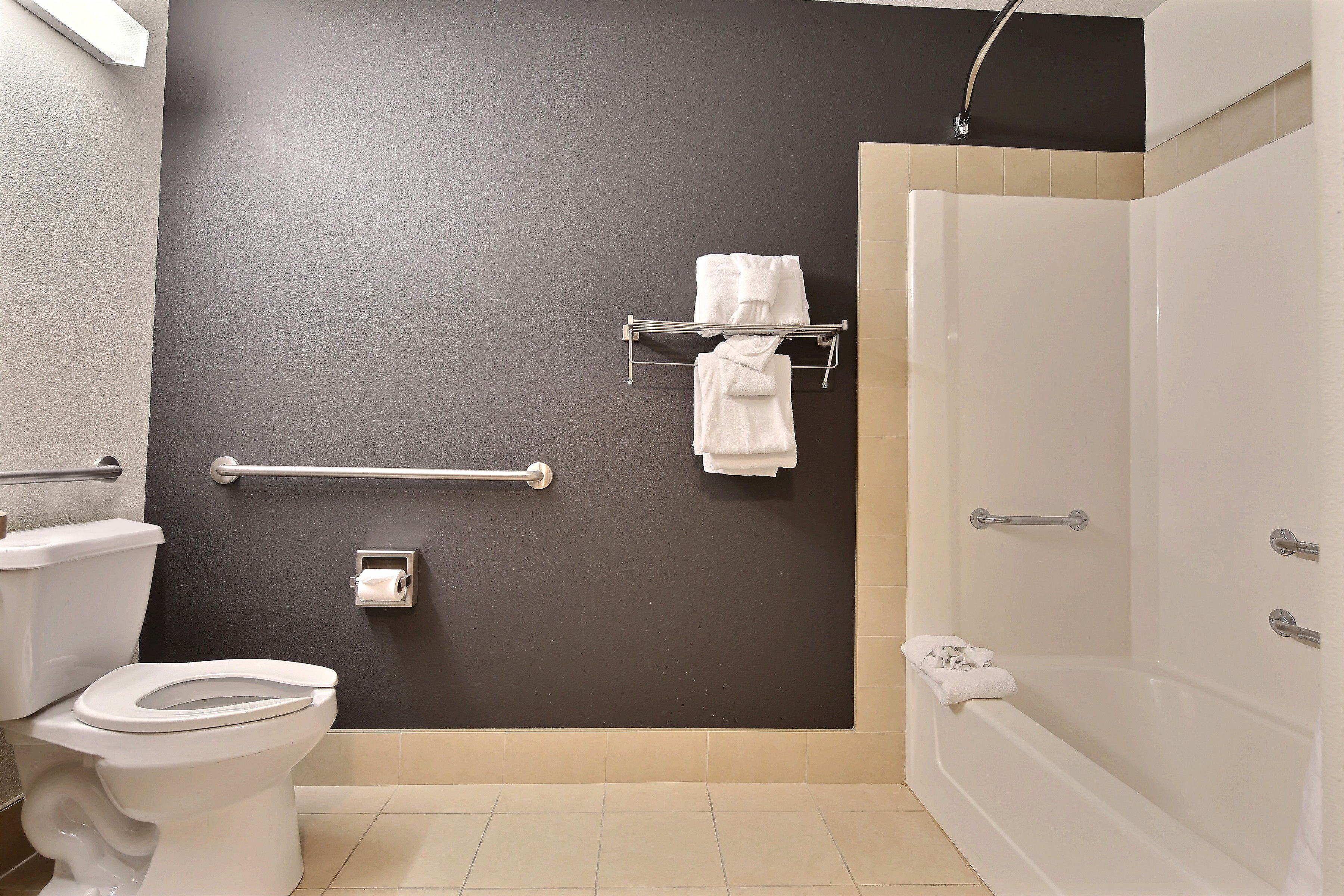 Un baño con inodoro, toallero con toallas, secamanos y zona de ducha.