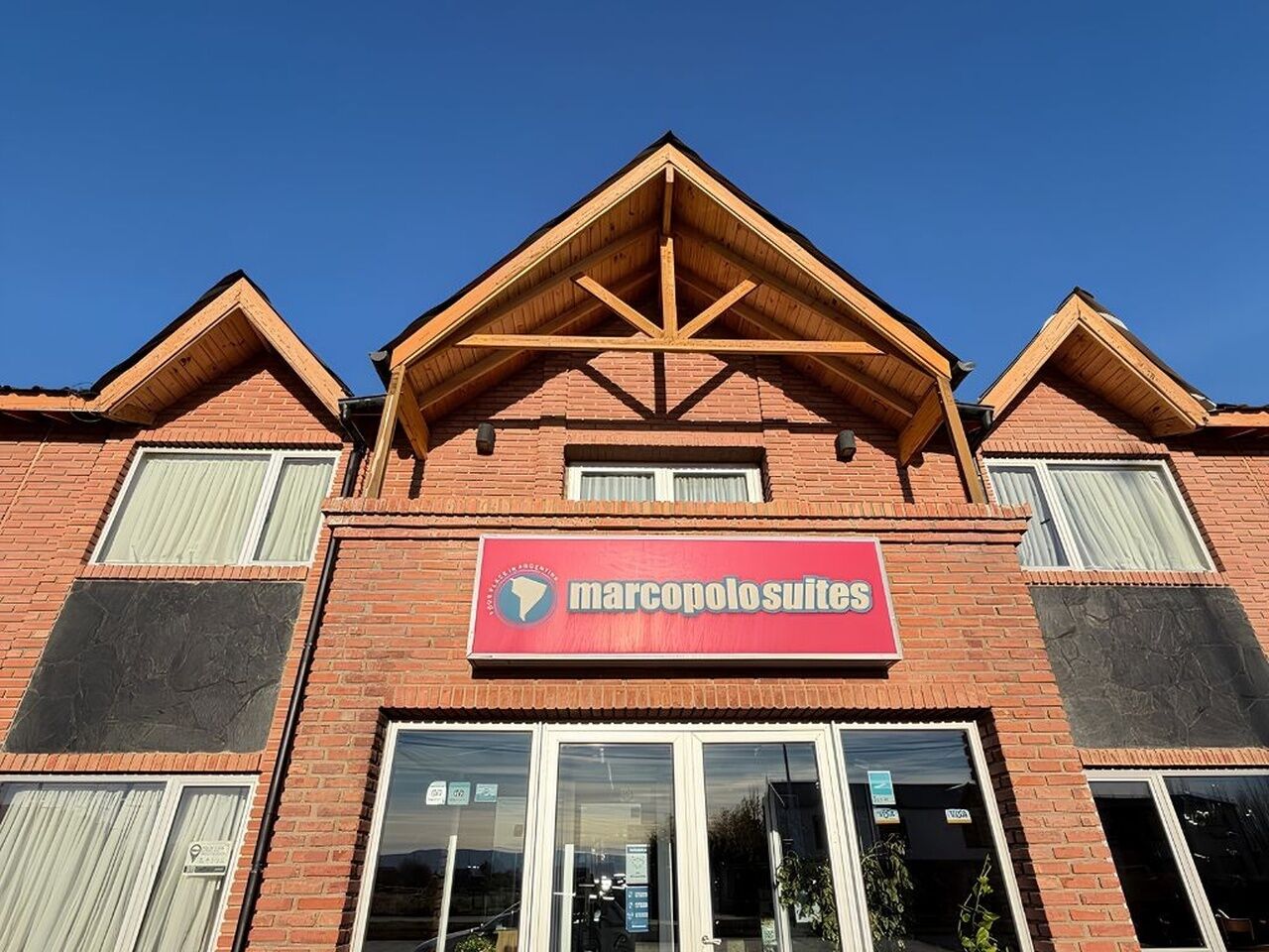 En bygning med et rødt skilt, der viser 'marcopolosuites', og en murstensfacade.