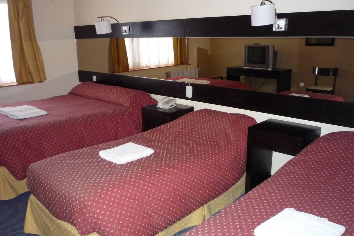 Een hotelkamer met twee bedden, een televisie, een spiegel en een telefoon.