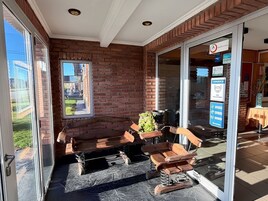 Un patio con muro de ladrillo, puerta de vidrio y mobiliario para exterior.