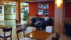 Un vestíbulo con mostrador de recepción, zona de estar y una pared con carteles de viajes.