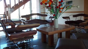 Un amplio salón con una escalera de madera, un ventanal grande y una pared decorada con carteles de viajes.
