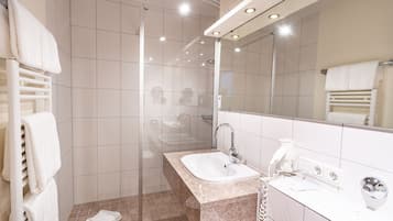 A modern bathroom with a glass shower enclosure, a standalone sink, and a large mirror.