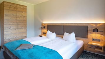 A hotel room with a large bed, wooden wardrobe, bedside lamps, and a headboard with built-in lighting.