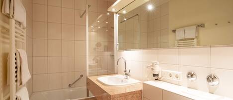 A modern bathroom with a walk-in shower, a sink, and a large mirror.