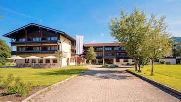 A hotel with a paved entrance, outdoor seating, and a well-maintained lawn.