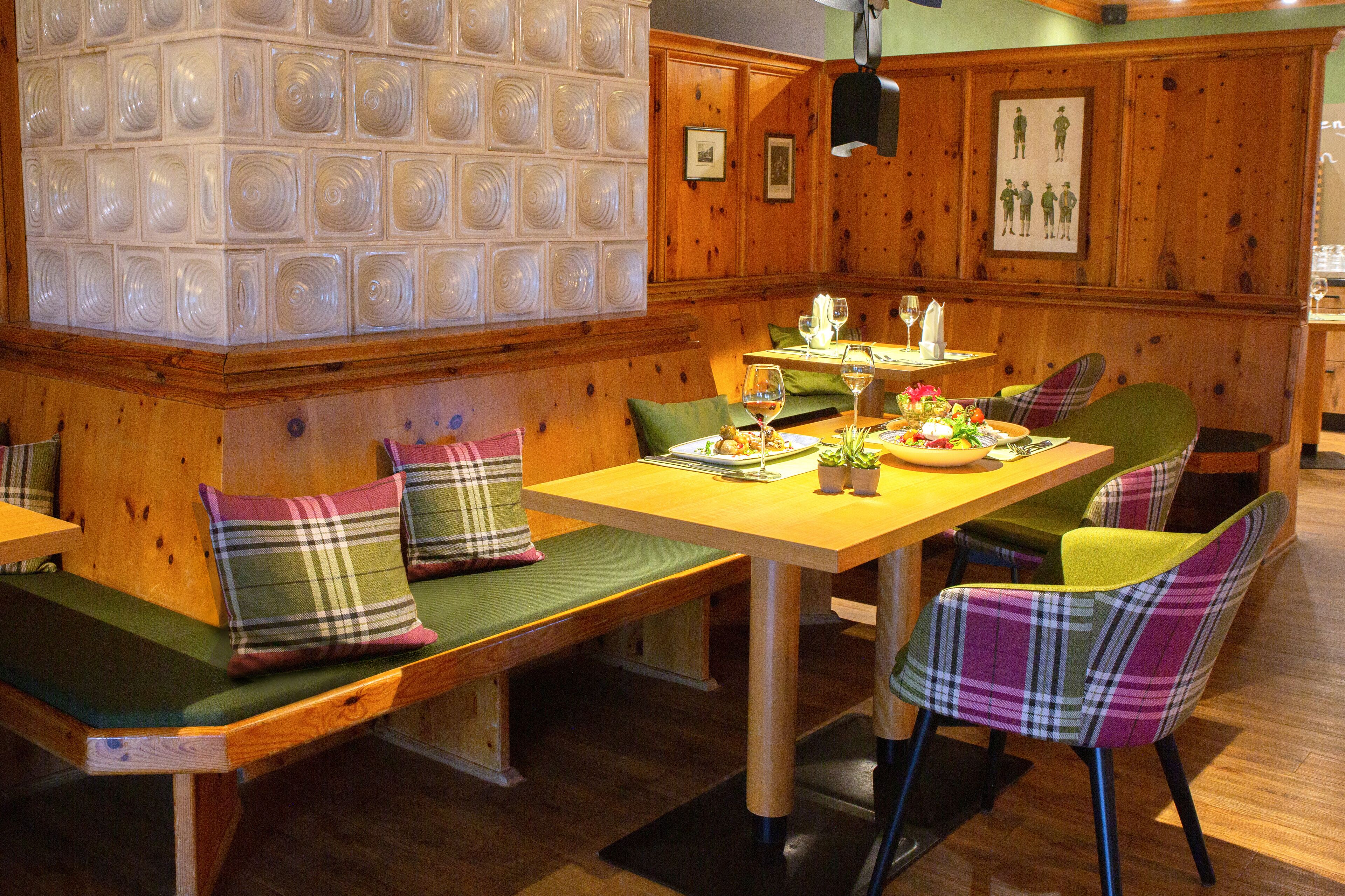 A wooden interior with a long table, benches, and plaid-patterned chairs.