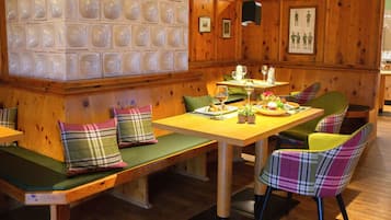 A wooden interior with a long table, benches, and plaid-patterned chairs.