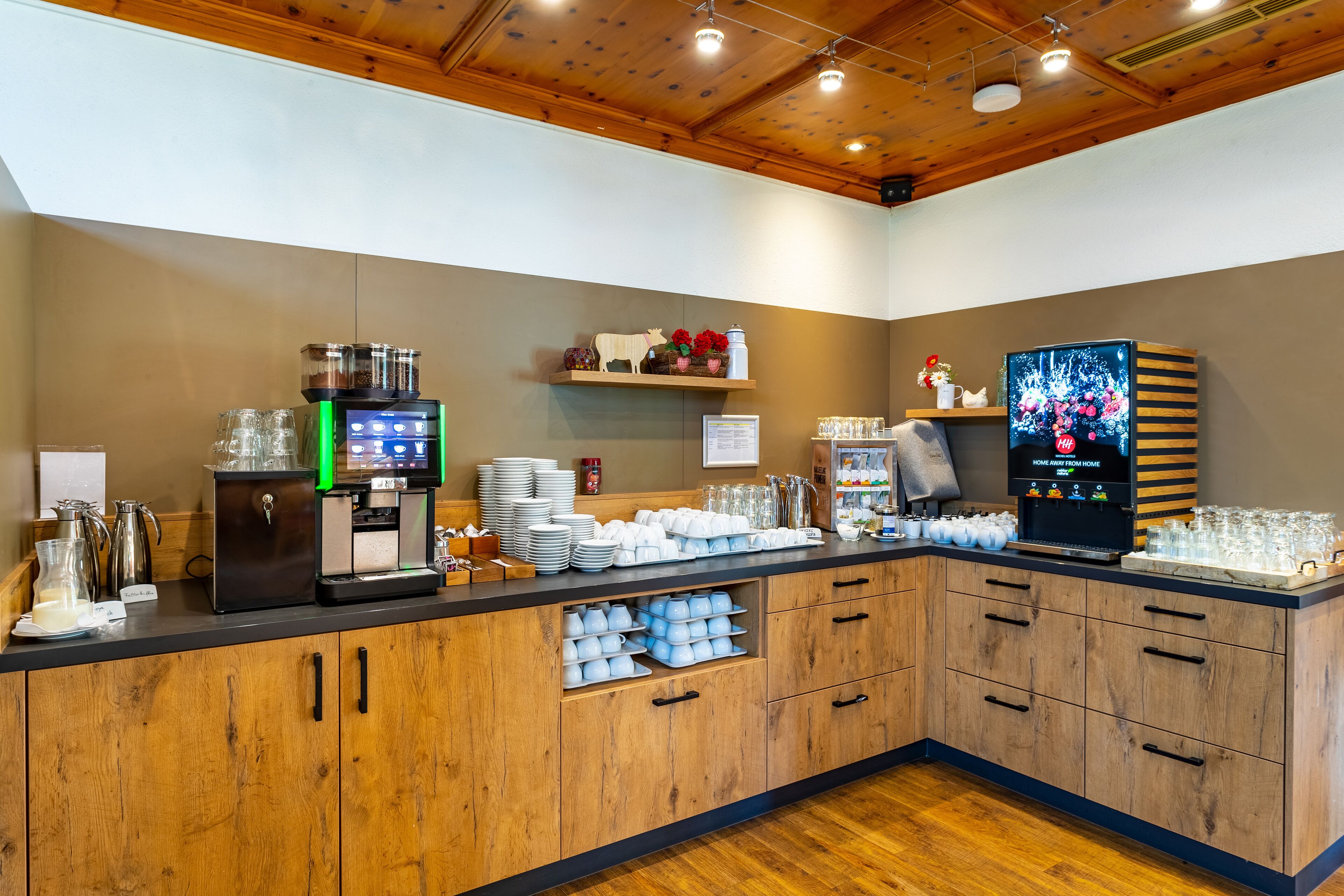 A buffet setup with a coffee station, glassware, and a television.