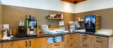 A buffet setup with a coffee station, glassware, and a television.
