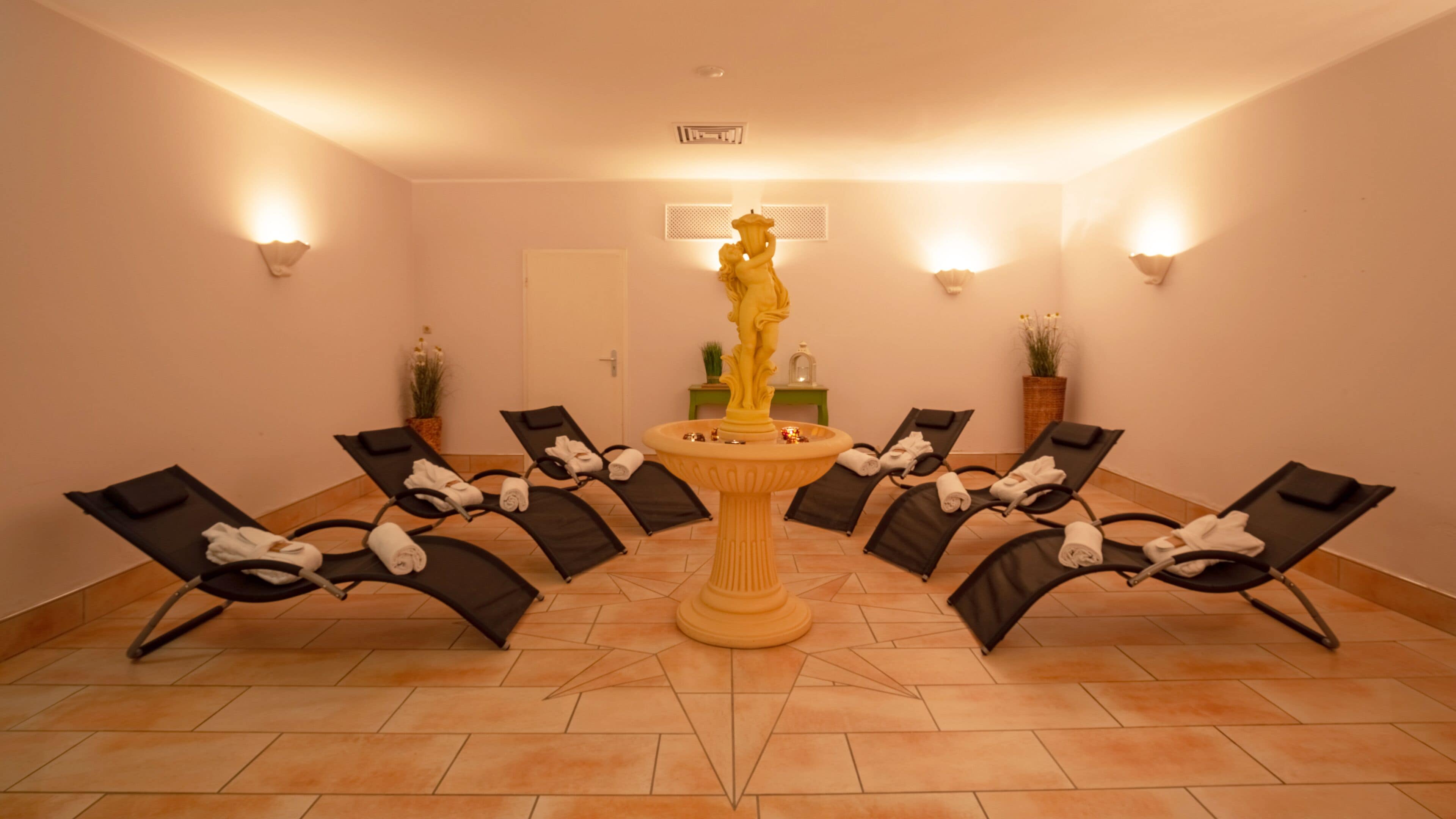 A room with six reclining chairs arranged in a semi-circle around a central fountain.