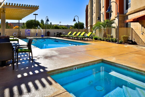 Una piscina al aire libre, sombrillas, sillones reclinables de piscina