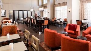 A spacious hotel lobby with multiple seating areas, including tables and chairs, and a bar area. - Hampton Inn & Suites Las Vegas South (Henderson)
