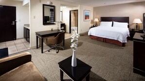 A hotel room with a bed, desk, chair, and a small table with a vase. - Hampton Inn & Suites Las Vegas South (Henderson)