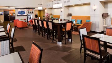 A hotel lobby with a reception desk, seating areas, and a large screen displaying a program.