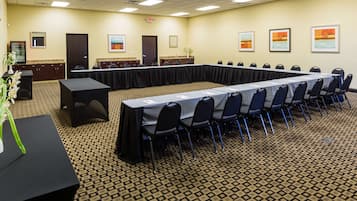 A conference room with a long table, chairs, a podium, and framed artwork on the walls.