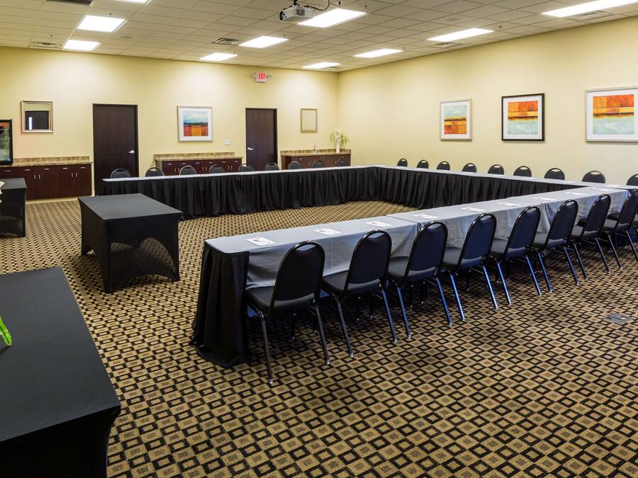 A conference room with a long table, chairs, a podium, and framed artwork on the walls.