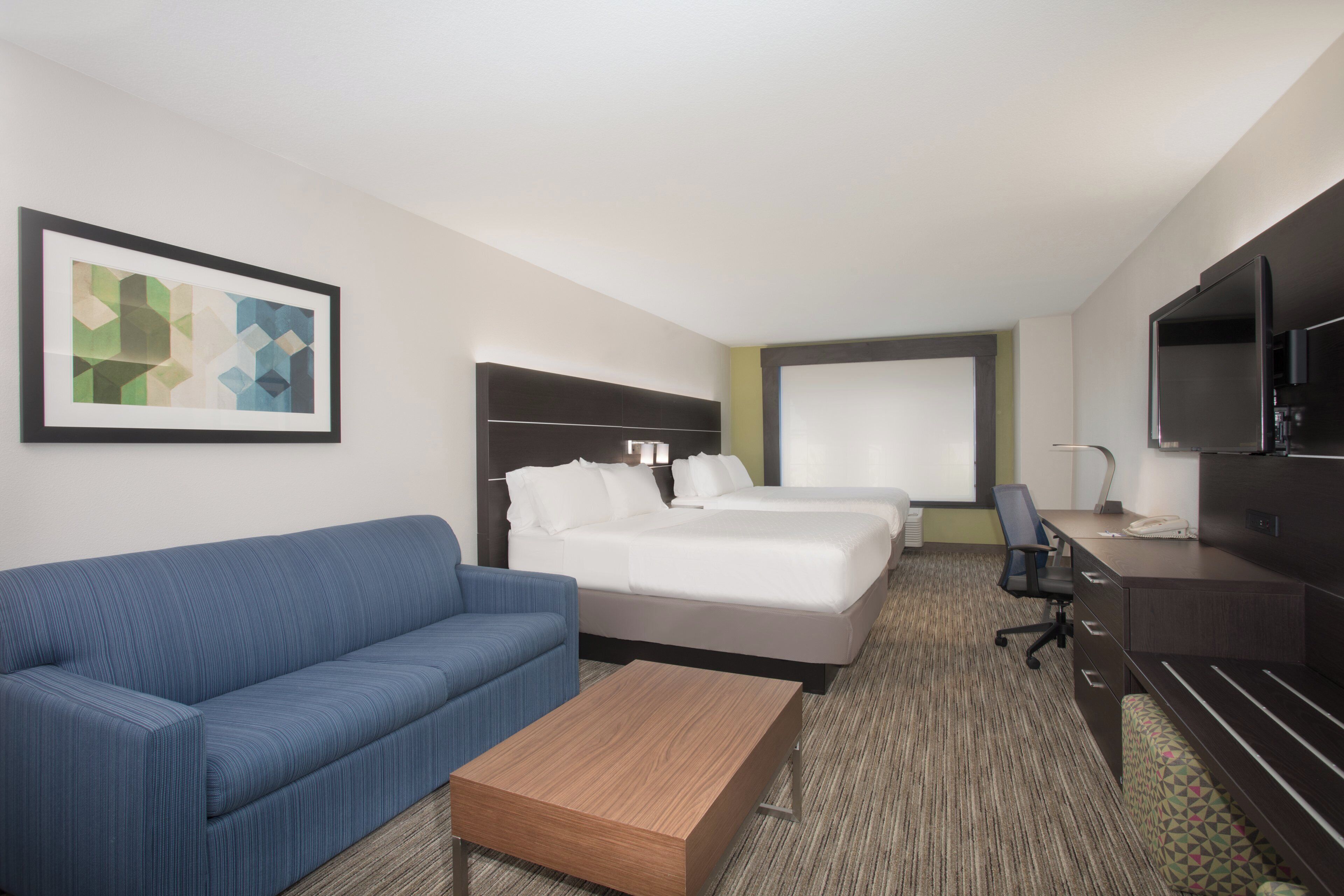 A hotel room with a bed, a sofa, a desk, and a TV.