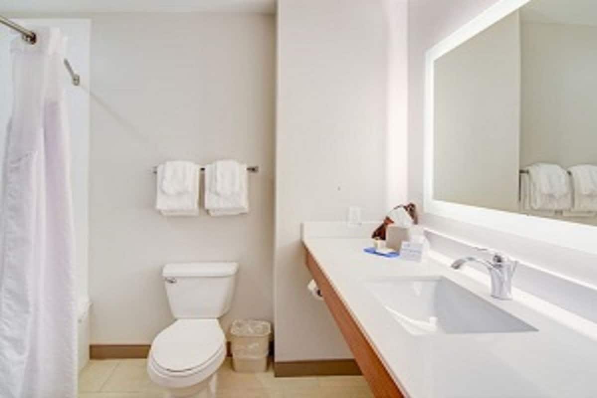 A bathroom with a toilet, sink, and mirror.