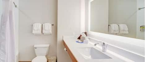 A bathroom with a toilet, a sink, a mirror, and two towels hanging on the wall.