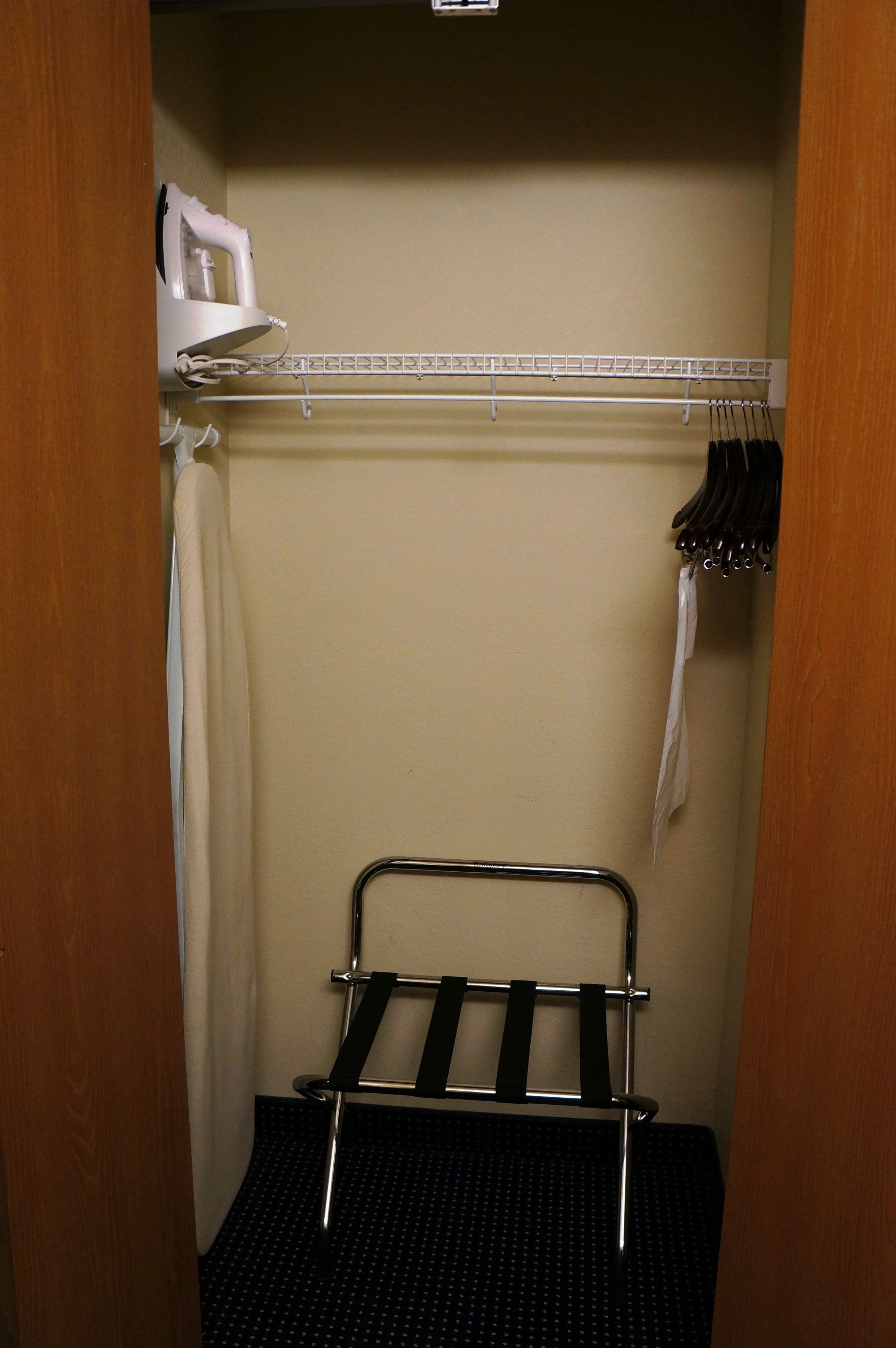A compact bathroom with a shower, a towel rack, and a small shelf with toiletries.