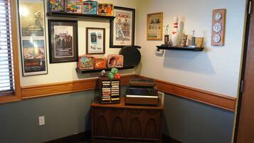 A room with a wooden cabinet displaying various items, a wall with framed movie posters, and a shelf with decorative objects.
