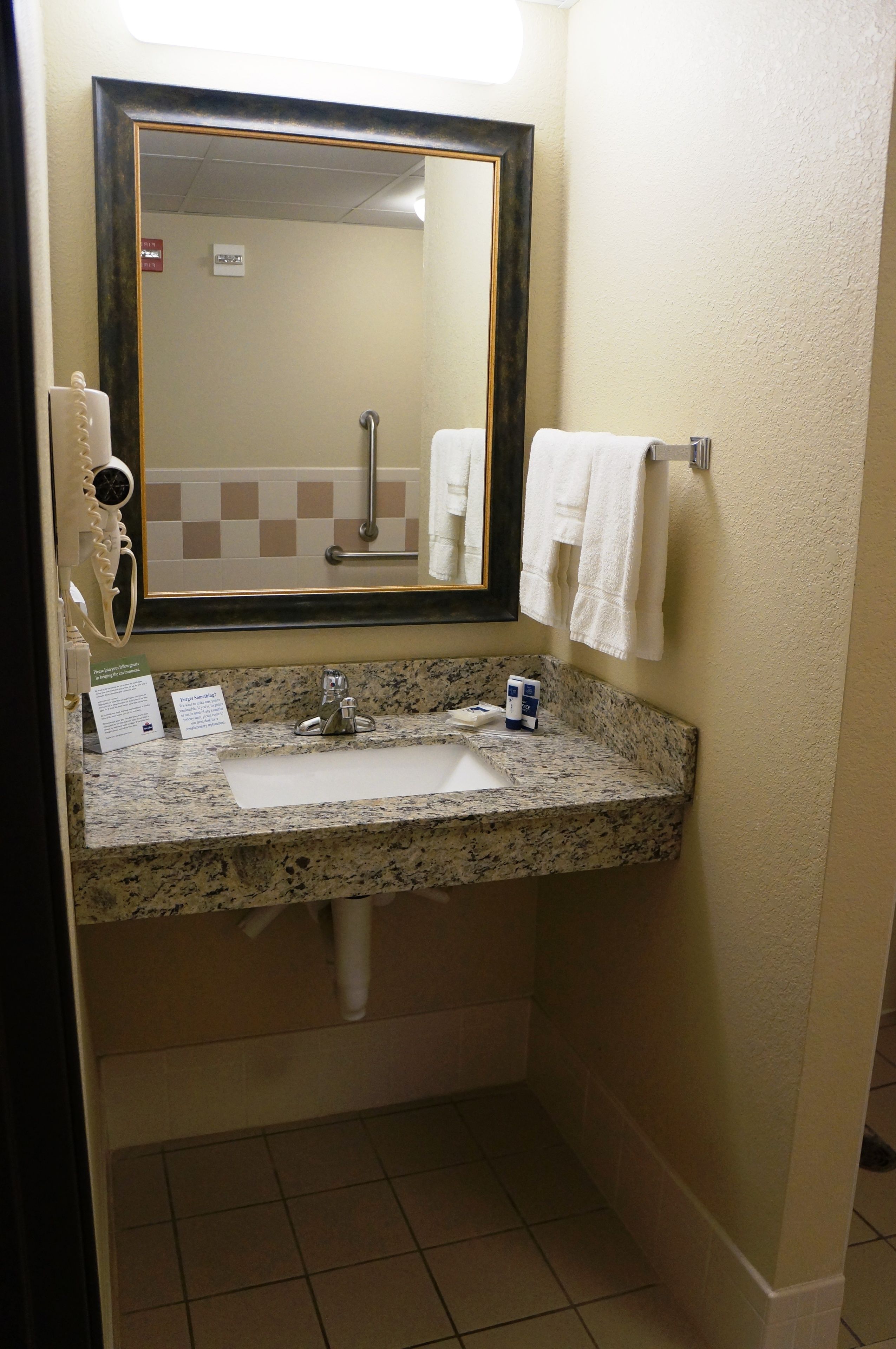 Un bagno con lavabo in granito, uno specchio, un portascopevoli e un asciugamani ad aria.