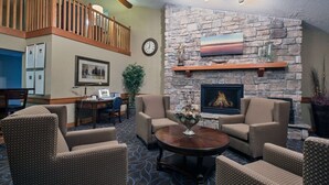 Una sala de estar acogedora con chimenea de piedra, asientos cómodos, un comedor y una escalera que conduce a un nivel superior.