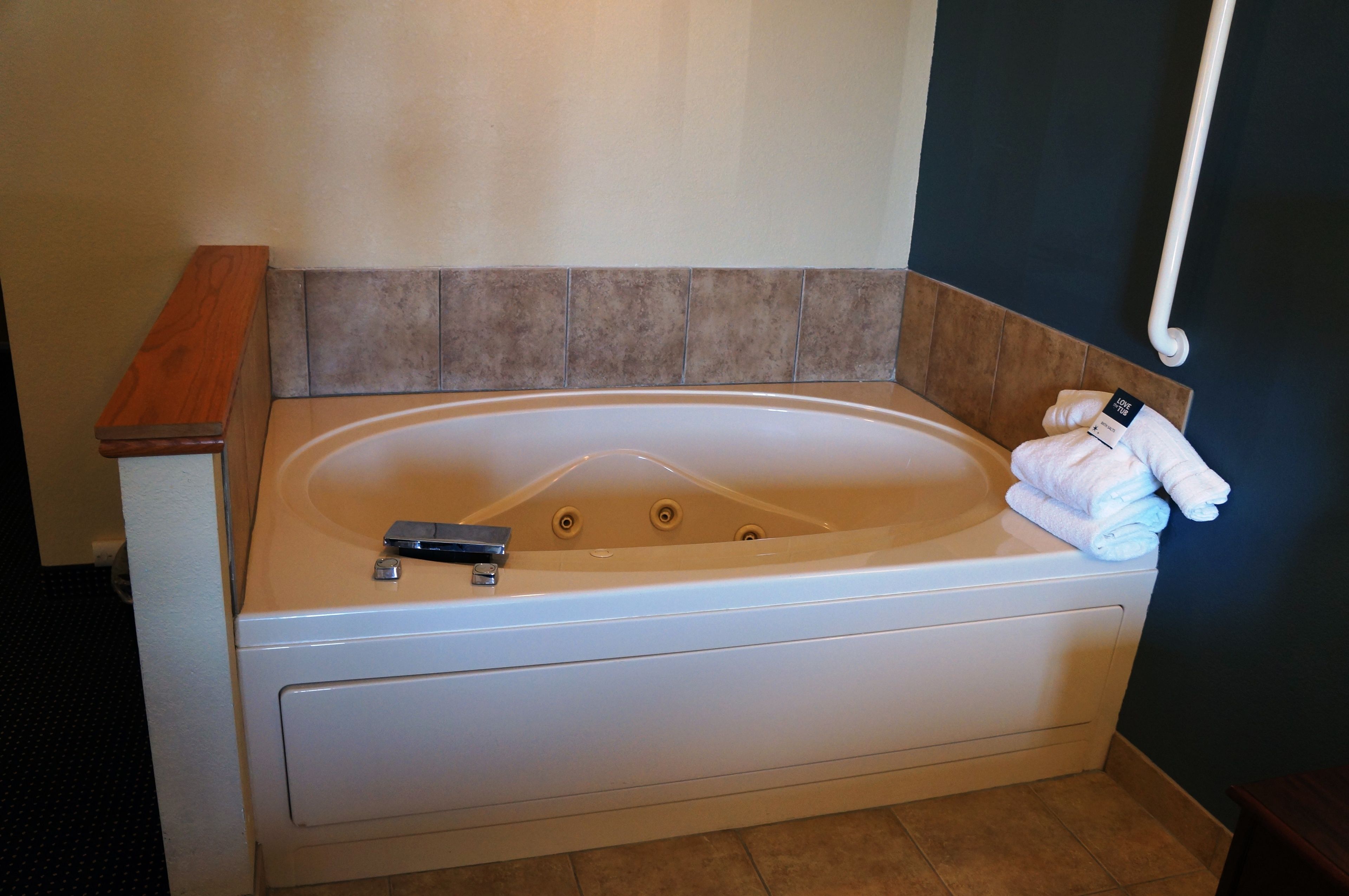 Un baño moderno con una bañera independiente, un banco de madera y un perchero para toallas.