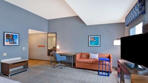 Una habitación de hotel con escritorio, sofá, televisión y cama.