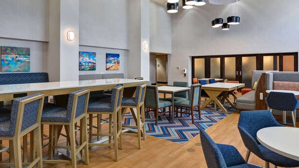 Un moderno vestíbulo de hotel con asientos de madera y tapizados, una mesa grande e iluminación contemporánea.